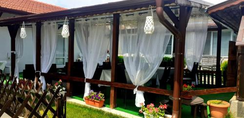 a screened in porch with white curtains and plants at Guest Rooms Simona in Opanets