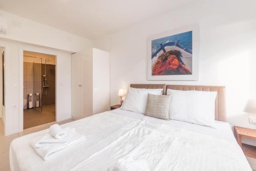 a white bedroom with a large bed and a bathroom at Villa Belveder in Pag