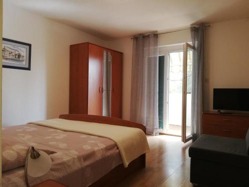 a bedroom with a bed and a tv and a window at Mitan apartman in Tučepi