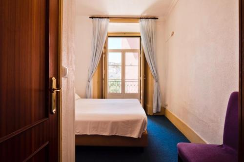 ein kleines Schlafzimmer mit einem Bett und einem Fenster in der Unterkunft Residencial Geres in Lissabon