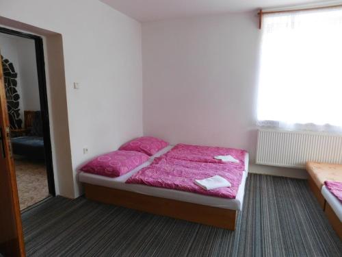 a bedroom with a bed with pink sheets and a window at Pension U Mojmíra in Rokytnice nad Jizerou