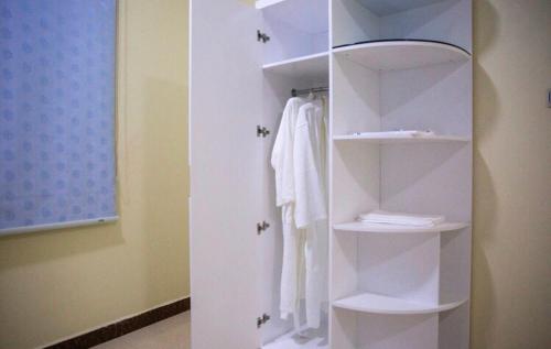 a white closet with white towels on shelves at Open in Buraydah