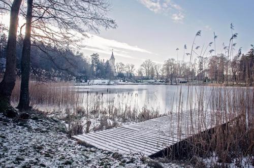 a bridge over a lake with a church in the background at Hotel Bursztynowy Pałac in Koszalin