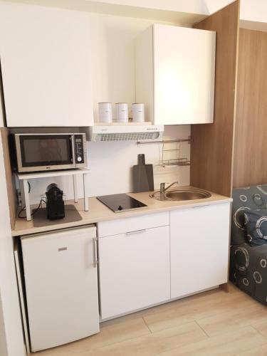 una cucina con armadi bianchi, forno a microonde e lavandino di Studio Carré d'Or a Nizza