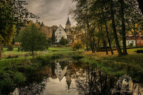 a reflection of a building in a body of water at Hotel Bursztynowy Pałac in Koszalin