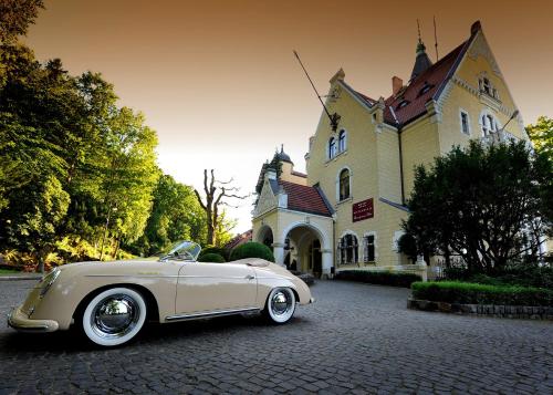 a white car parked in front of a building at Hotel Bursztynowy Pałac in Koszalin