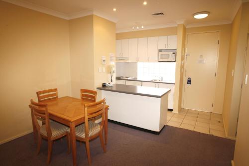 a kitchen with a table and chairs and a refrigerator at Maclin Lodge Motel in Campbelltown