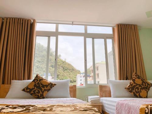 a bedroom with two beds and a large window at Green Mountain Hostel in Cat Ba