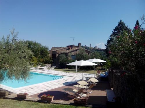 a pool with chairs and umbrellas next to a house at Podere Bellavista in San Gimignano