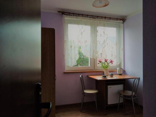 a room with a table and a window with a vase of flowers at Na Skwerku in Stronie Śląskie
