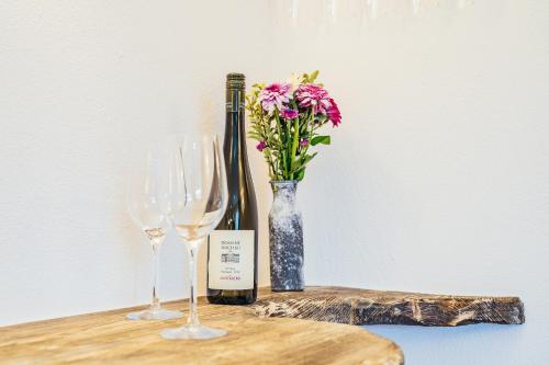 a table with two wine glasses and a vase with flowers at Wachau-Living in Dürnstein