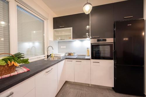 a kitchen with white cabinets and a black refrigerator at Villa Fidelissima in Kaštela