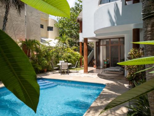 a swimming pool in front of a house with plants at Casa Sonoma - Charming Condos Minutes from Beach & Reef in Puerto Morelos