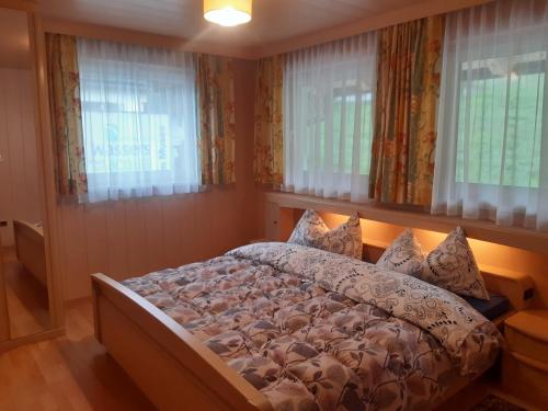 1 dormitorio con 1 cama en una habitación con ventanas en Alpen Ferienwohnung Ill en Lappago