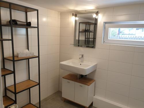 ein Badezimmer mit einem Waschbecken, einem Spiegel und Regalen in der Unterkunft HummelHaus 3 in Lindau in Lindau