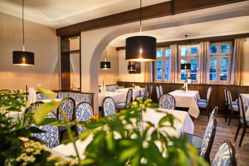 um restaurante com mesas e cadeiras brancas e janelas em Hotel Landgraf em Schwalmstadt