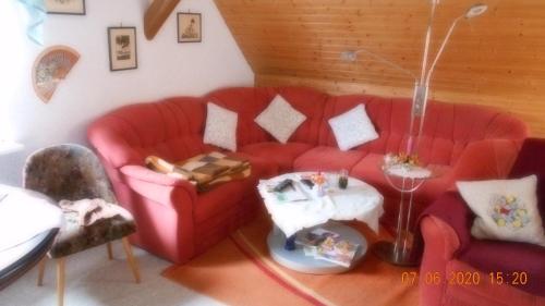a living room with a red couch and a table at Vermiete sehr schönes Apartment in Dankerode im Harz in Dankerode