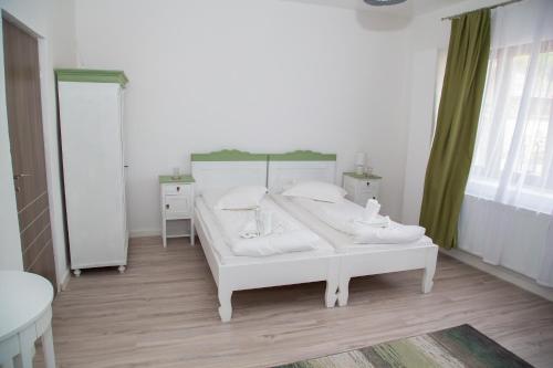 a white bedroom with a white bed and a window at Cosbuc Residence & Villa in Sighişoara