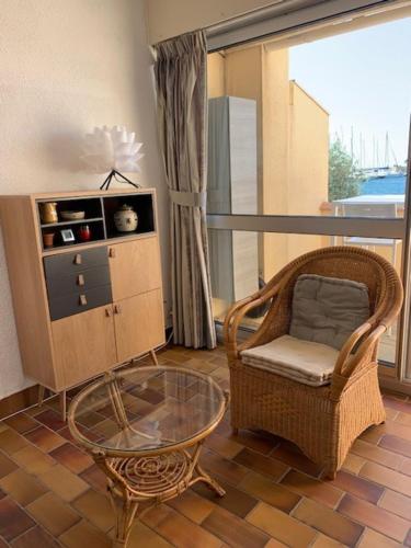 un salon avec une chaise et une table en verre dans l'établissement EN BORD DE MER, à Gruissan