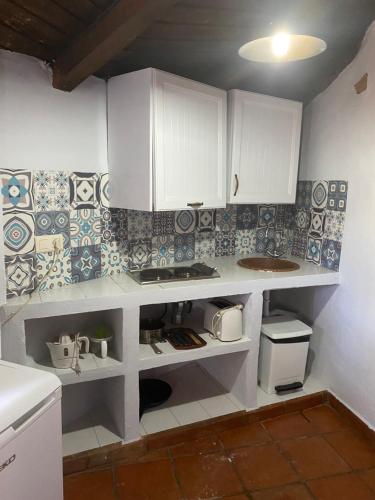 a kitchen with white cabinets and blue and white tiles at complejo rural el prado in Logrosán