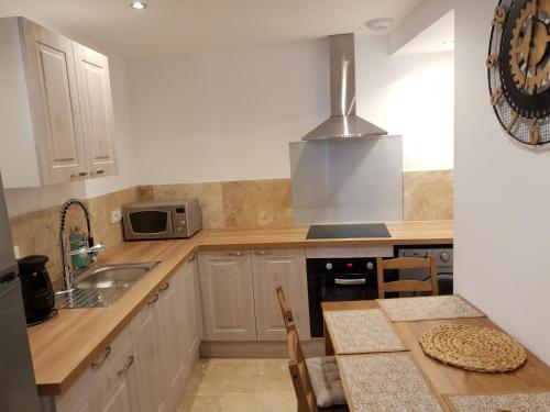 a kitchen with white cabinets and a sink and a counter at Le soleil de Malaucène in Malaucène
