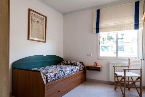sypialnia z łóżkiem, krzesłem i oknem w obiekcie CASA CON JARDIN-WIFI FREE w mieście L'Escala