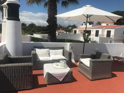 a patio with chairs and an umbrella and a table at CASA CARVOEIRO in Poço Partido