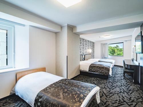 a hotel room with two beds and a desk at APA Hotel Sapporo Susukino Eki Minami in Sapporo