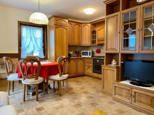 a kitchen with a table with chairs and a television at Villa Tisot in Fiera di Primiero