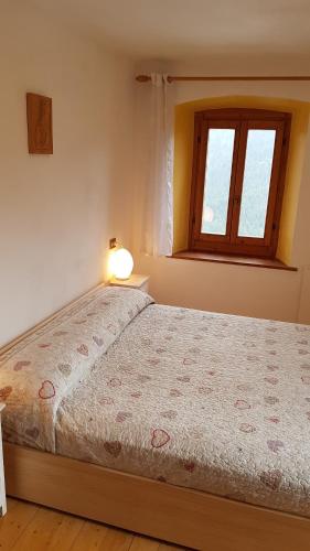 a bedroom with a bed with a lamp and a window at Appartamento Comelico Dolomiti in Candide