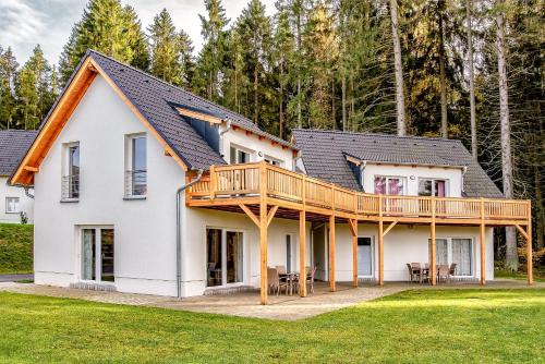 a house with a large deck on the front of it at Lipno Club in Frymburk