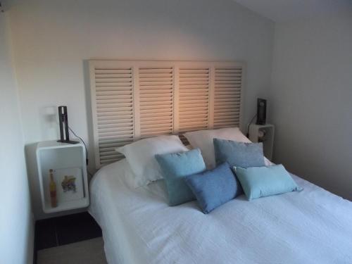 une chambre avec un lit blanc avec des oreillers bleus dans l'établissement TERRASSE DES OCRES, à Roussillon
