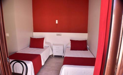 two beds in a room with red and white at Hostal Playa Candor in Rota
