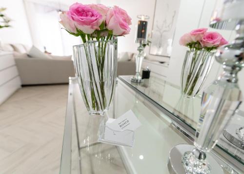 dwie wazy z różowymi różami na szklanym stole w obiekcie BIANCO APARTMENTS w Świnoujściu