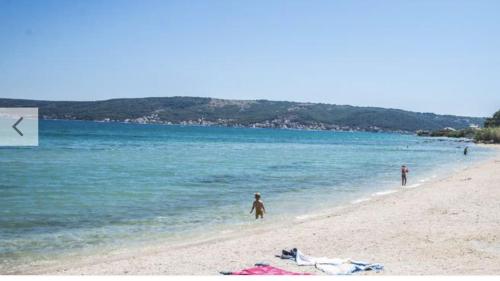 two people standing on a beach near the water at Apartman Laura in Kaštela