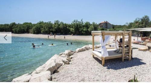 a beach with a swing and people in the water at Apartman Laura in Kaštela