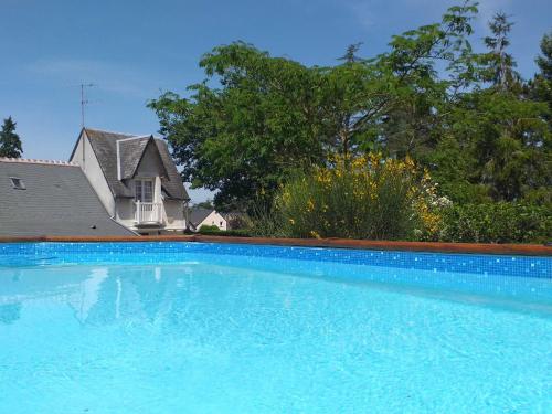une grande piscine bleue devant une maison dans l'établissement Le Jardin De Josseline, à Amboise