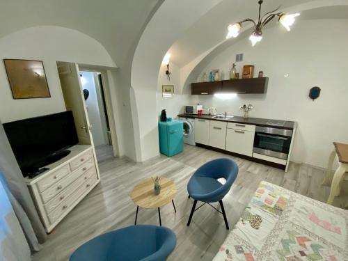 a living room with blue chairs and a kitchen at Apartmány Kováčska in Košice