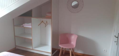 a pink chair sitting in a room under a staircase at La mélodie des oiseaux in Grand-Bourg
