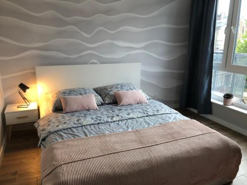 a bedroom with a bed with two pink pillows at Apartament Alfa with free parking in Poznań