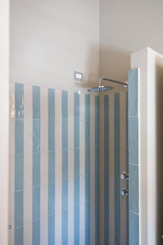 a shower with a blue and white striped shower curtain at Diecidodici BoutiqueRooms in Sirolo