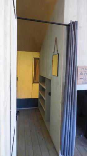 a small room with a yellow wall and a shelf at La tente de la plage in Plouha
