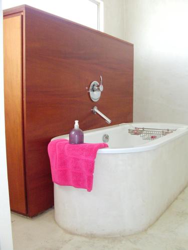 a bath tub with a pink towel next to a wooden door at Bentley on the Beach in Umhlanga