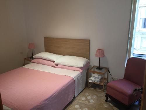 1 dormitorio con 2 camas y 1 silla en Rose Building Apartment, en Cospicua