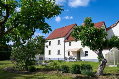 ein großes weißes Haus mit rotem Dach in der Unterkunft Ferienwohnung Erika in Laußnitz
