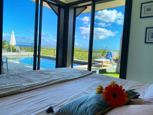 a bedroom with a bed with a view of a pool at LA MAISON DES JADES in La Saline les Bains