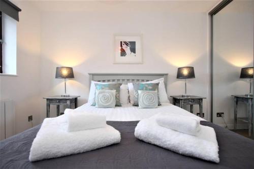 a bedroom with a large white bed with two tables at Bijou Merchant City Apartment with Parking (Albion 1) in Glasgow