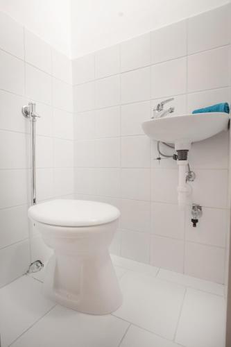 a white bathroom with a toilet and a sink at Nyaraló Apartman in Siófok