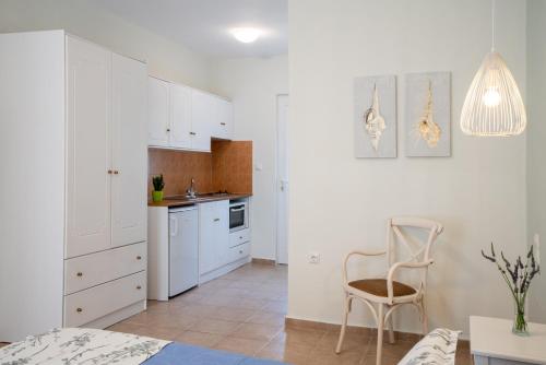 a kitchen with white cabinets and a chair and a table at Almira Hotel in Troulos
