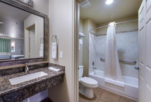 bagno con lavandino, servizi igienici e specchio di Eagle Ford Inn a Floresville